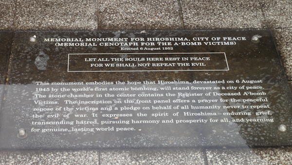 a plaque reads: MEMORIAL MONUMENT FOR HIROSHIMA, CITY OF PEACE (MEMORIAL CENOTAPH FOR THE A-BOMB VICTIMS) Erected 6 August 1952.  LET ALL THE SOULS HERE REST IN PEACE FOR WE' SHALL NOT REPEAT THE EVIL.
This monument embodies the hope that Hiroshima, devastated on 6 August 1945 by the world's first atomic bombing, will stand forever as a city of peace. The stone chamber in the center contains the Register of Deceased A-bomb Victims. The inscription on the front panel offers a prayer for the peaceful repose of the victims and a pledge on behalf of all humanity never to repeat the evil of war. It expresses the spirit of Hiroshima-enduring grief. transcending hatred, pursuing harmony and prosperity for all, and yearning for genuine, lasting world peace.